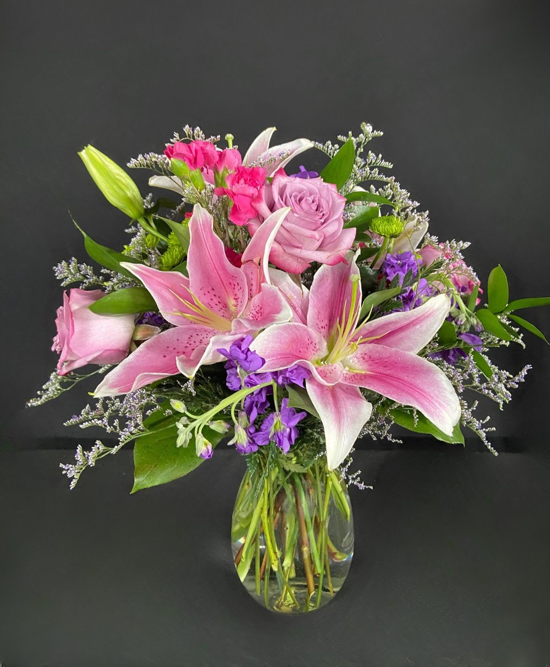 Starstruck - Grab their attention and make them starstruck with this breathtaking arrangement center around beautiful and fragrant stargazer lilies. Also includes purple roses, purple stock, green button poms, hot pink mini carnations.
