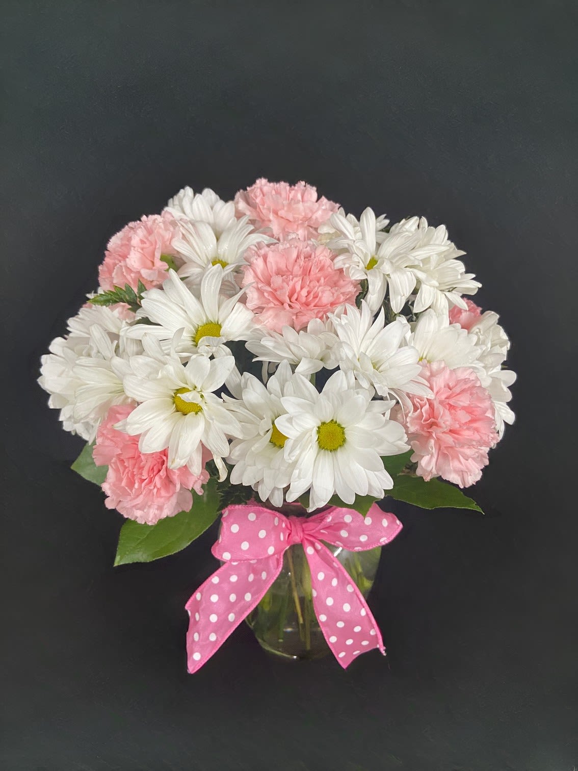 Rose &amp; Daisy Melody - An eye-catching bouquet of pink roses (deluxe &amp; premium sizes), pink carnations, and white daisies on a bed of greens. There is beauty in simplicity.