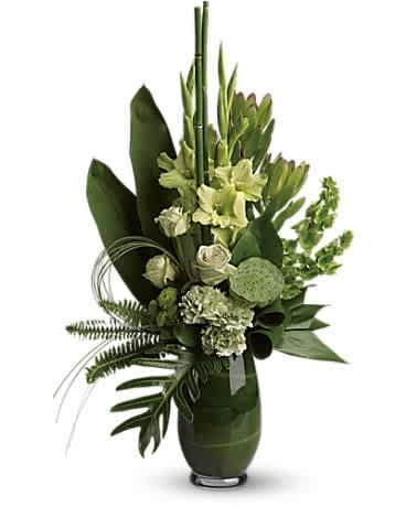 Green floral arrangement in a dark vase with tall stems and tropical leaves
