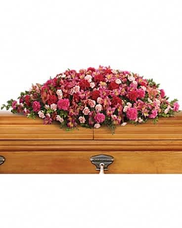Pink and red floral casket spray on a wooden coffin