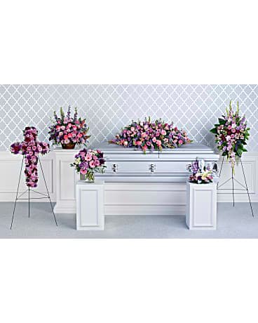 Funeral casket spray with pink and purple flowers on a white casket
