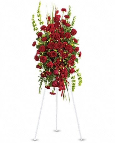 Tall standing spray of red roses with green accents on a white easel
