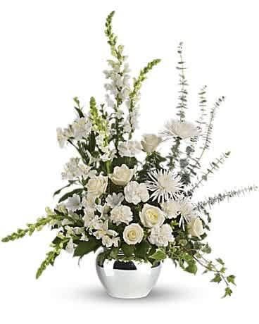 White floral arrangement in a silver vase with tall spires and trailing greenery
