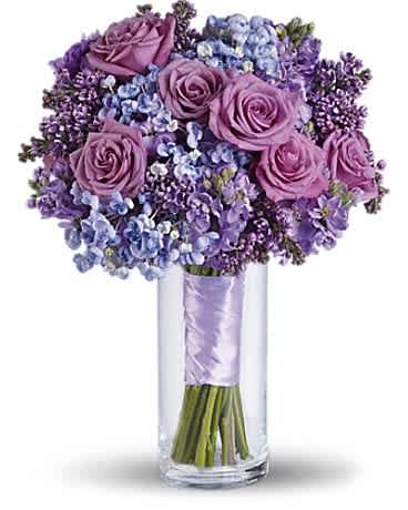Purple roses and blue-purple flowers in a clear glass vase