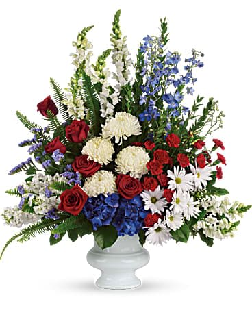 Red roses, white mums, blue flowers, and white daisies in a white vase