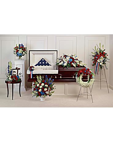 Patriotic funeral floral set with red, white, and blue arrangements around a casket