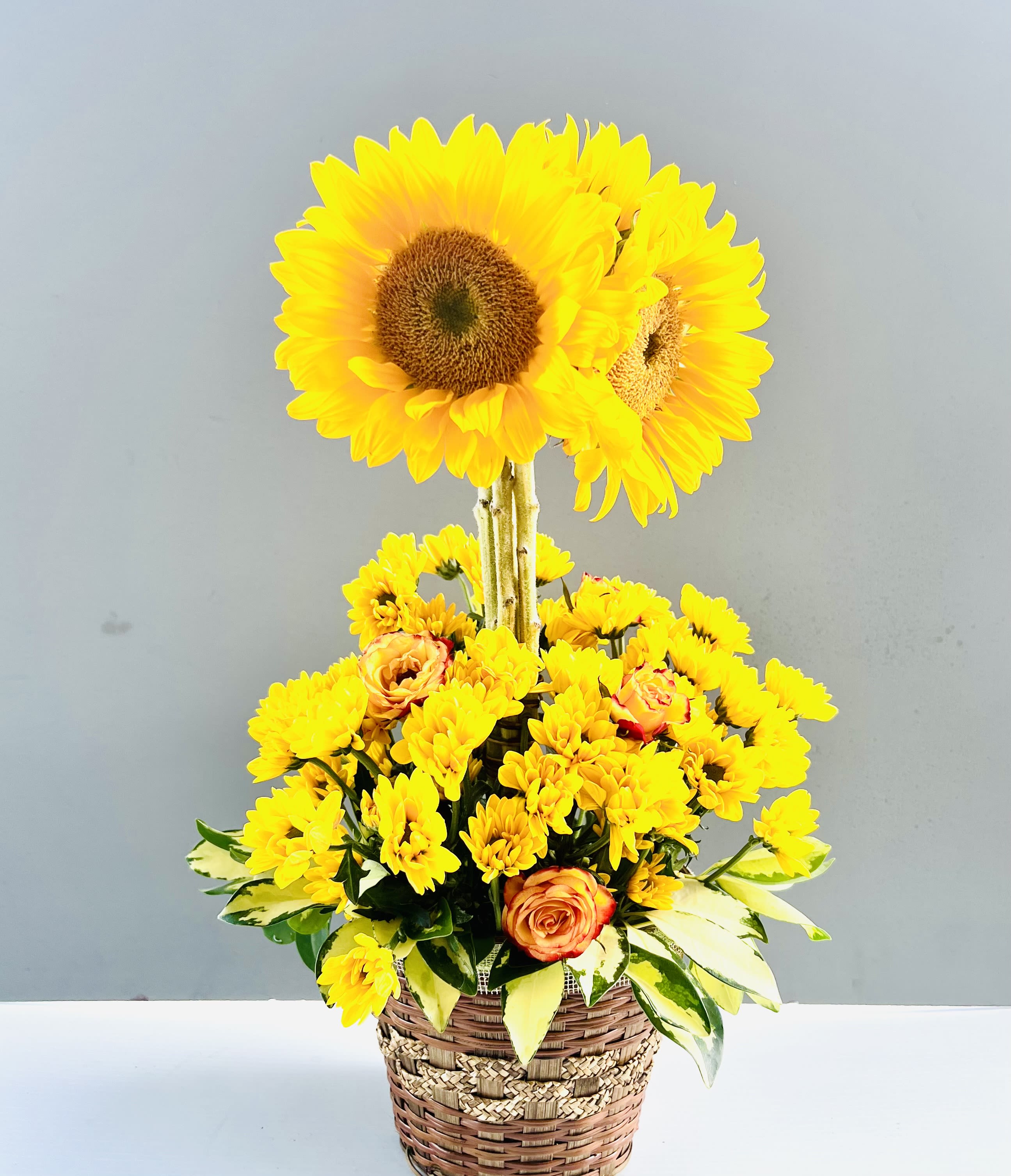 Yellow sunflowers and small yellow blooms in a woven basket