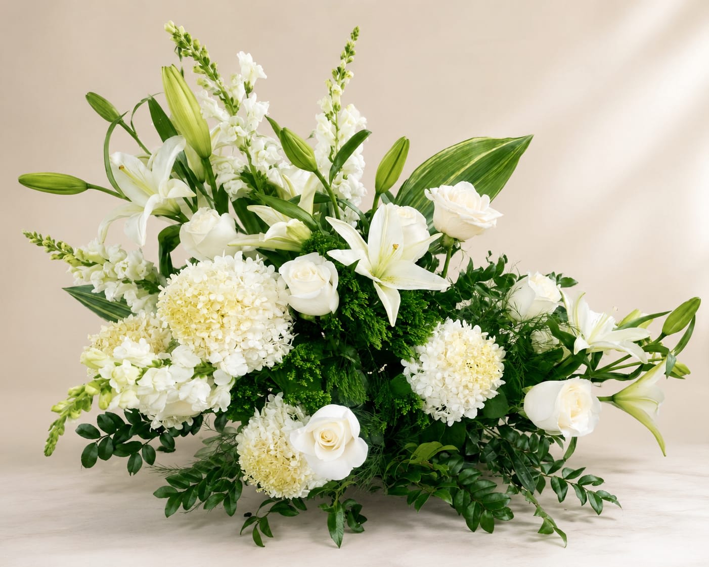White lilies and roses arranged with round white blooms in a low display.