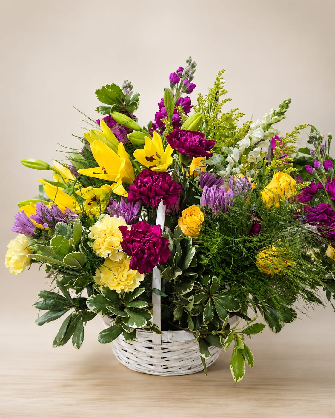 Basket arrangement of yellow lilies, purple flowers, and pink carnations
