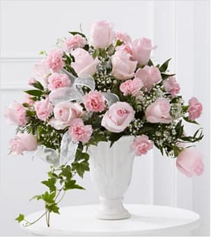 Deepest Sympathy Arrangement - The  Deepest Sympathy Arrangement is a presentation of grace and elegance to honor the life of the deceased. Pale pink roses and pink carnations are offset by baby's breath, variegated ivy, lush greens and a white sheer ribbon, gorgeously arranged in a designer white ceramic pedestal vase, to create a lovely way to express your warmest sentiments, offering comfort and peace with each blushing bloom. Also available in white, red, or yellow. Please note color preference in special instructions if other than pink.  S47-4554 