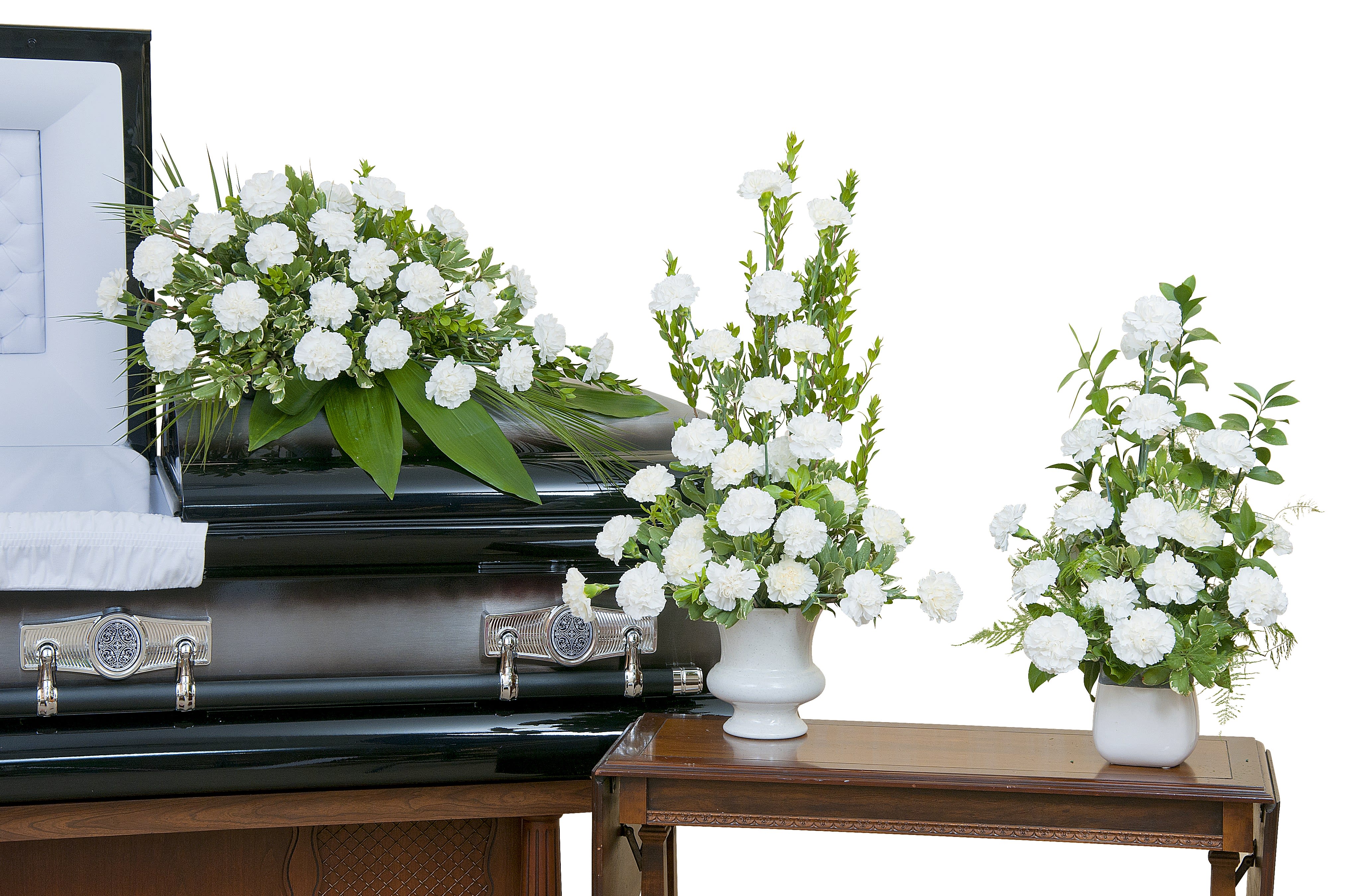 White floral funeral arrangement on a casket with two matching vase arrangements