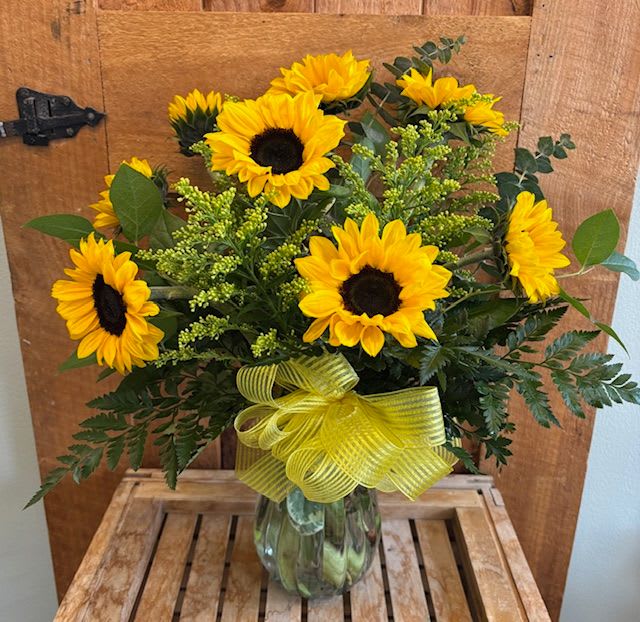 Sunflower bouquet in a glass vase with a yellow ribbon