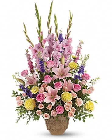 Tall mixed bouquet of pink lilies, roses, and purple flowers in a woven basket