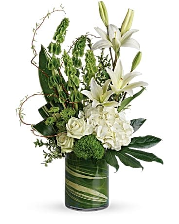 White lilies and roses arranged in a green glass vase