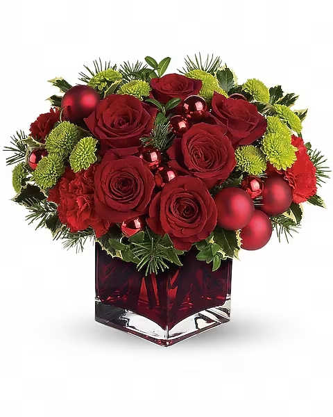Red roses and green mums in a red glass vase with holiday ornaments