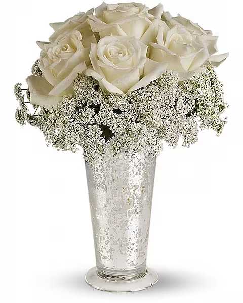 White roses arranged in a tall clear vase with baby's breath