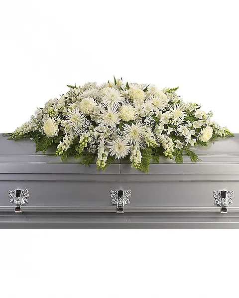 White funeral casket spray with mixed blooms on a silver casket