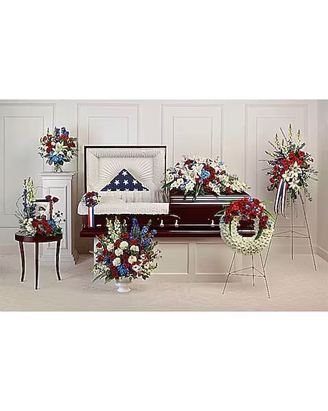 Funeral casket spray and standing floral tributes in red, white, and blue