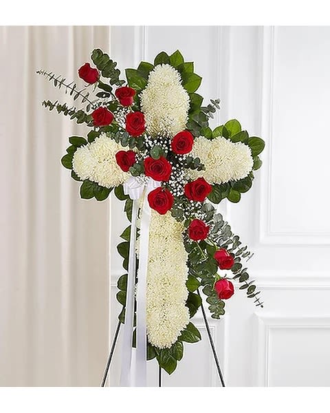 Standing floral cross with red roses and white blooms on an easel
