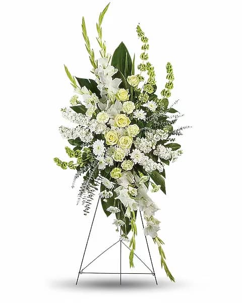 White floral standing spray on an easel with green accents