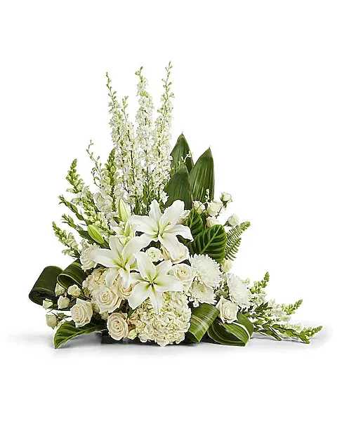 White lilies and roses arranged with tall white spikes and broad green leaves
