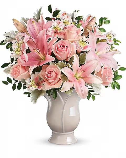 Pink lilies and roses arranged in a ceramic vase