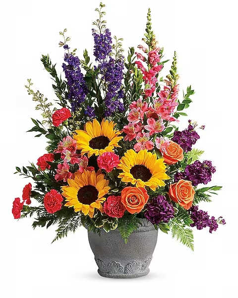 Colorful bouquet with sunflowers, roses, carnations, and purple spikes in a gray vase