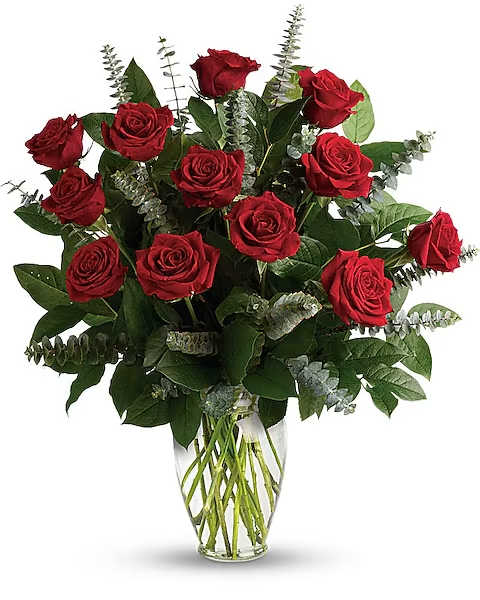 Red roses arranged in a clear glass vase with greenery
