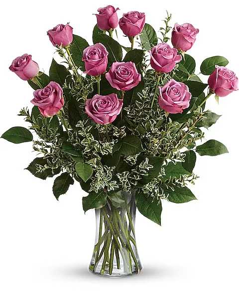 Pink roses arranged in a clear glass vase with greenery