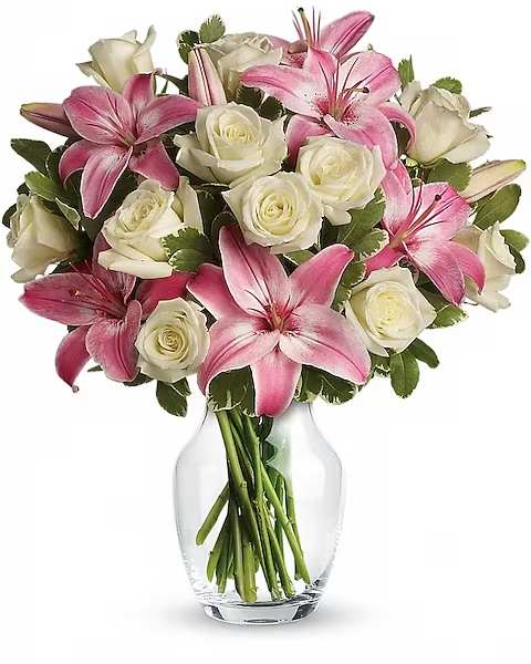 Pink lilies and white roses arranged in a clear glass vase