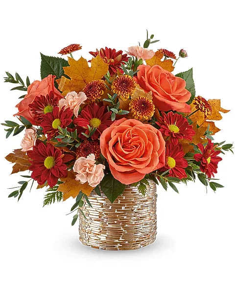 Autumn bouquet of orange roses and red daisies in a woven basket
