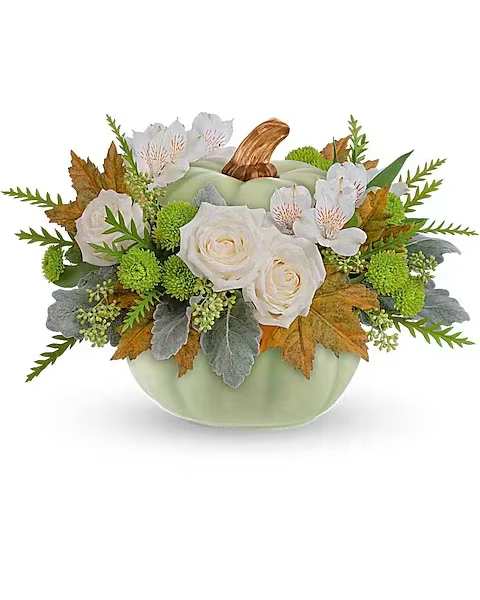 White roses and small white flowers in a pumpkin-shaped vase
