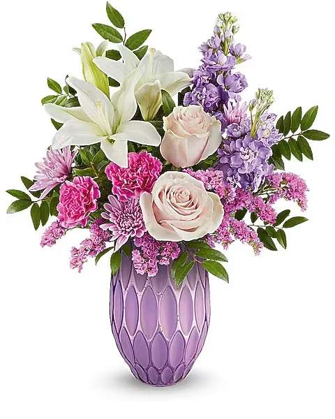Bouquet of white lilies, pink roses, and purple flowers in a lavender vase