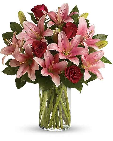 Pink lilies and red roses in a clear glass vase