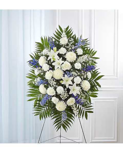 Standing funeral spray of white and blue flowers on an easel