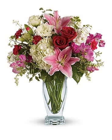 Pink lilies and red roses arranged in a clear glass vase