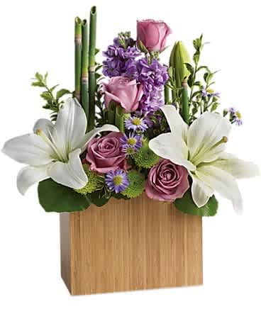 Arrangement of white lilies, pink roses, and purple flowers in a wooden box