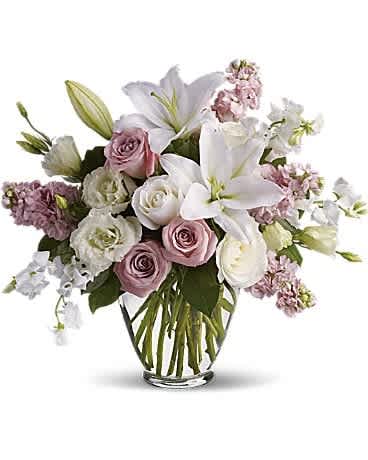Pink and white roses with lilies in a clear glass vase