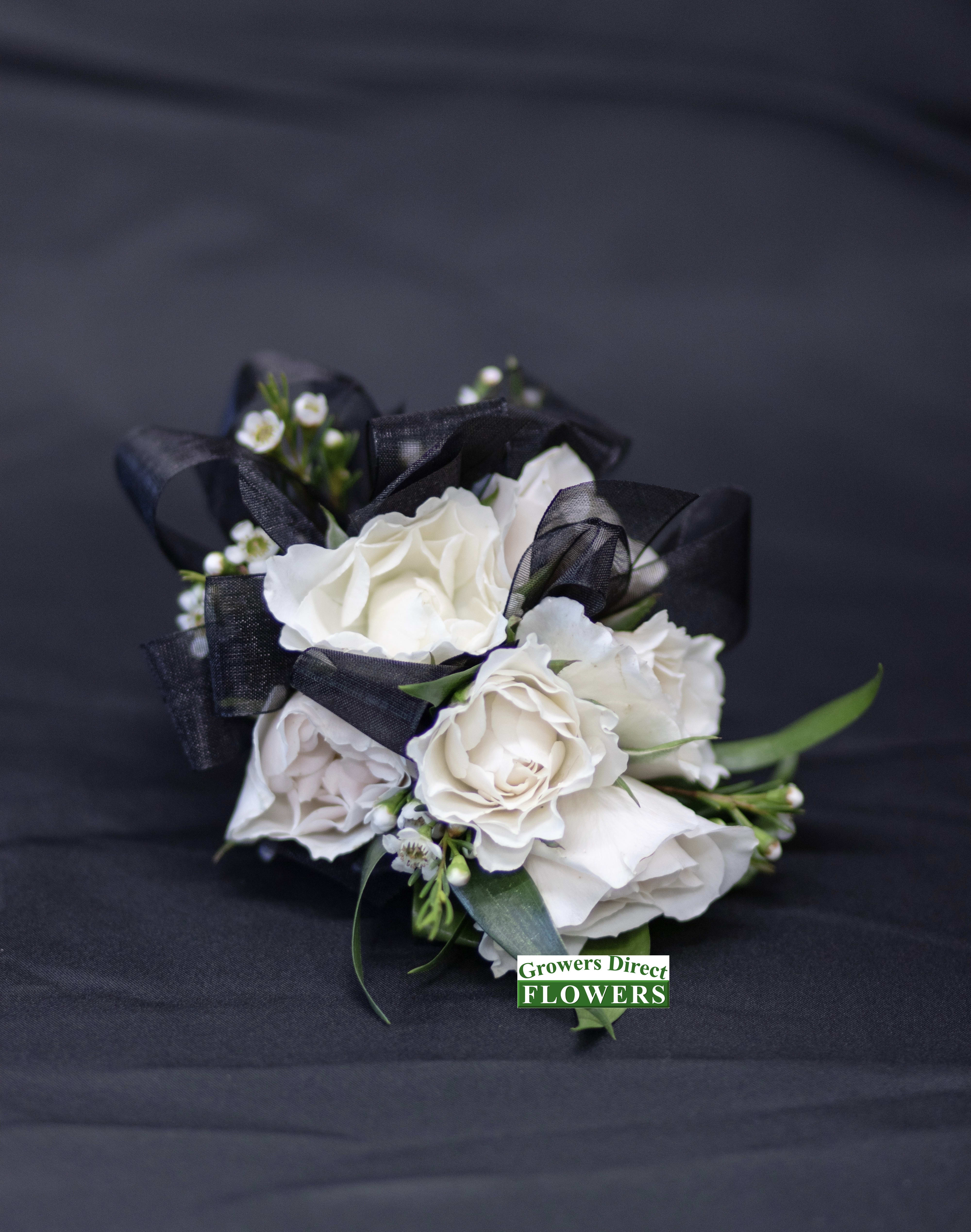 White rose bouquet with black ribbon on dark fabric