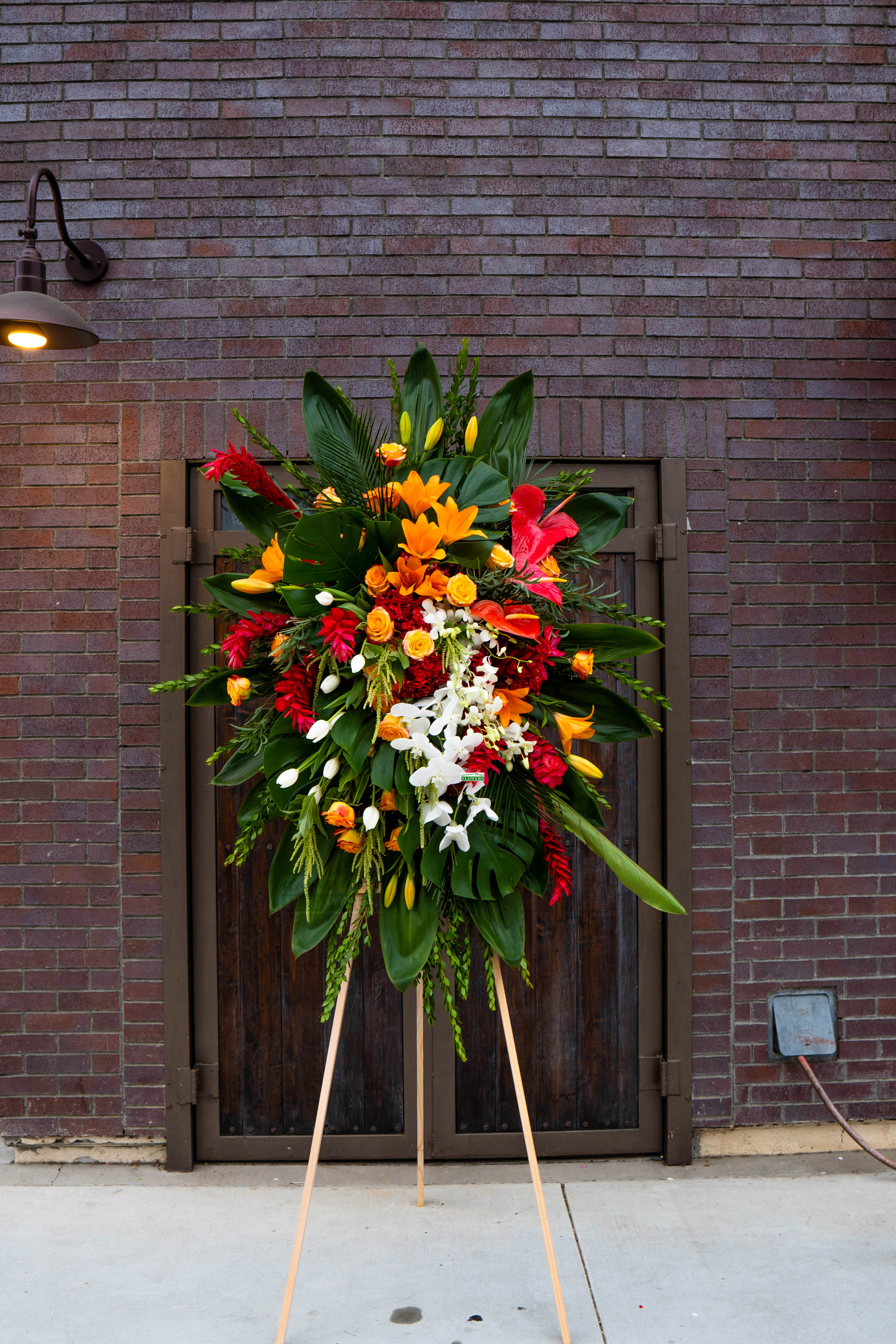 Large standing floral spray with red, orange, yellow, and white blooms