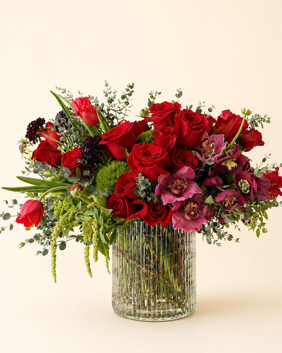 Red roses and pink orchids in a clear ribbed glass vase