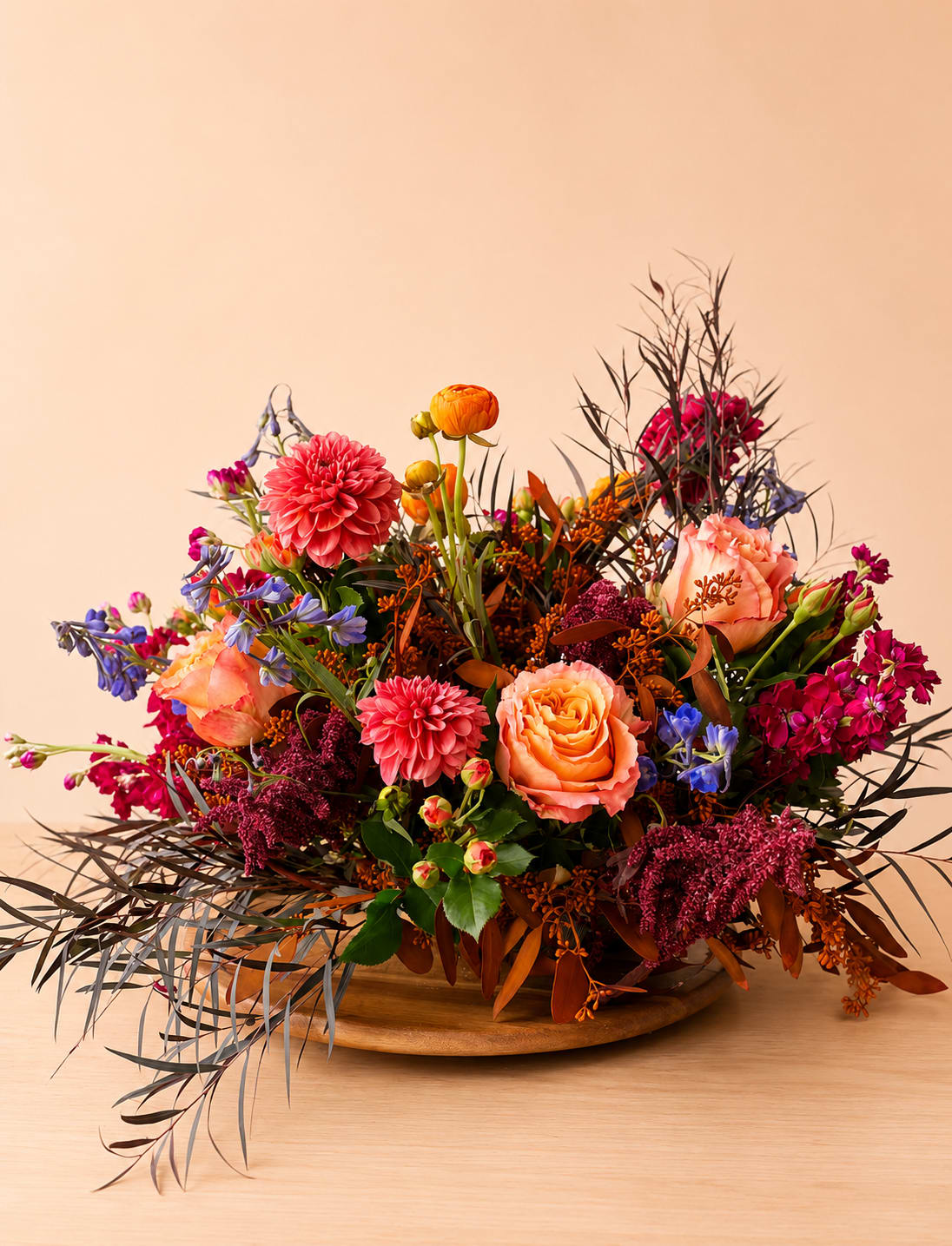Colorful mixed flower arrangement in a low wooden bowl