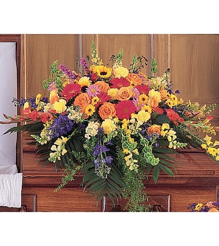 Large colorful floral arrangement on a wooden casket
