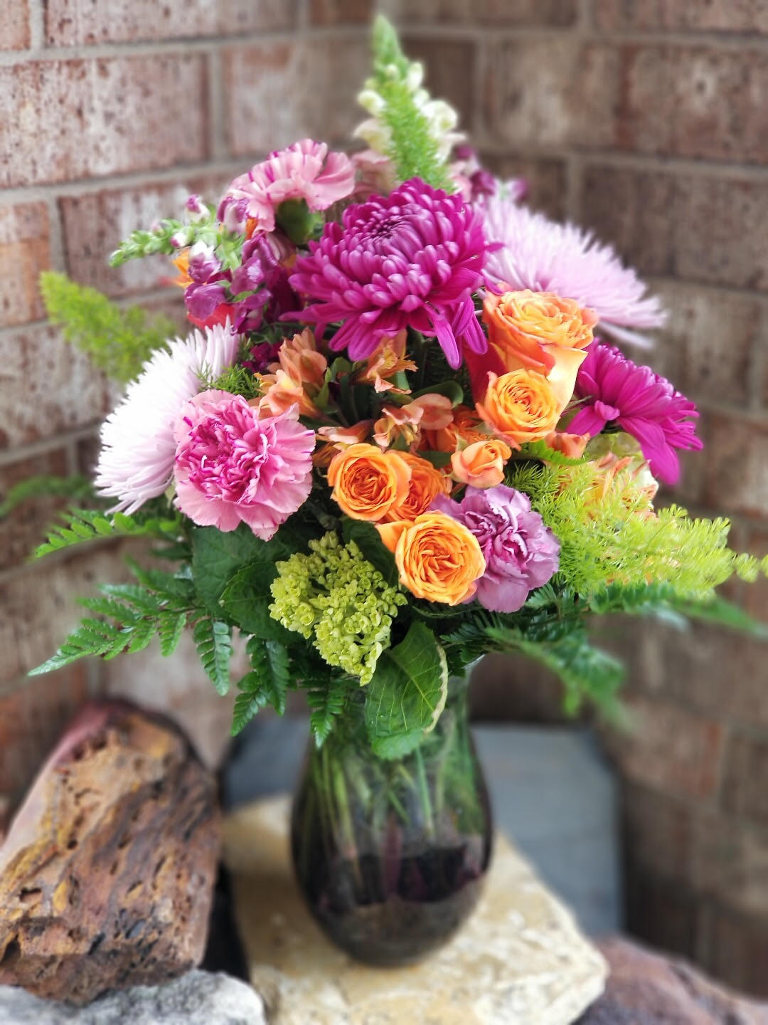 Mixed bouquet of pink, purple, and orange flowers in a glass vase