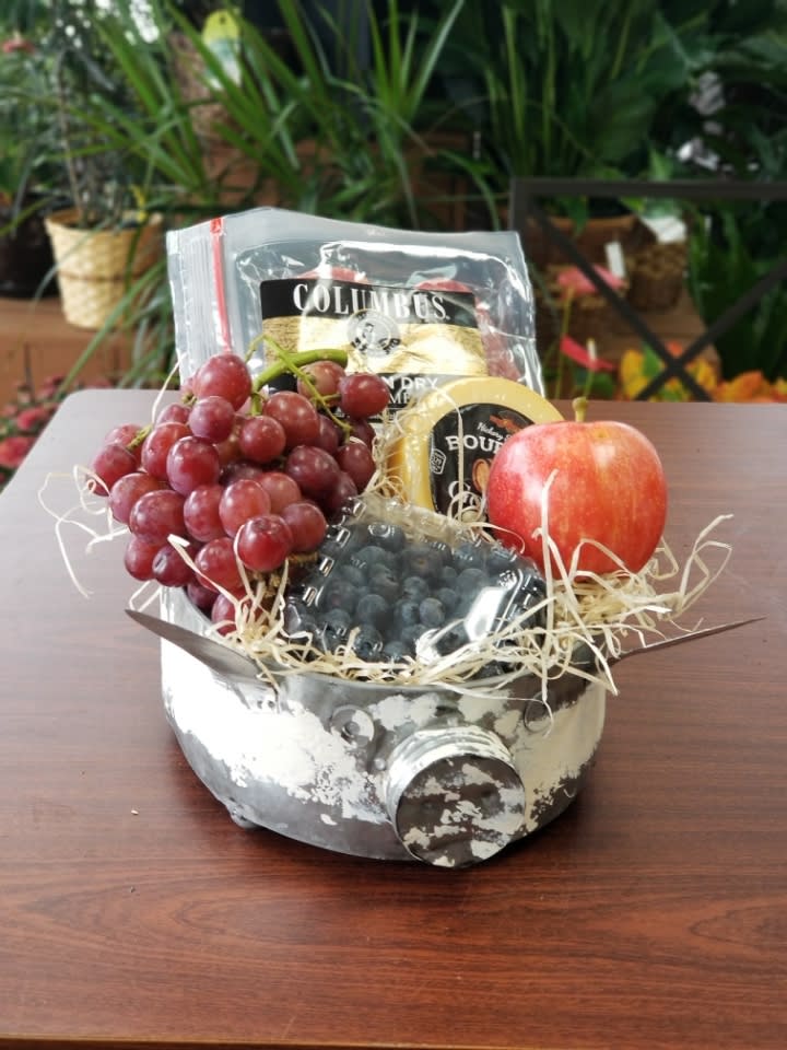 Fruit gift basket with grapes, an apple, and packaged snacks in a metal container