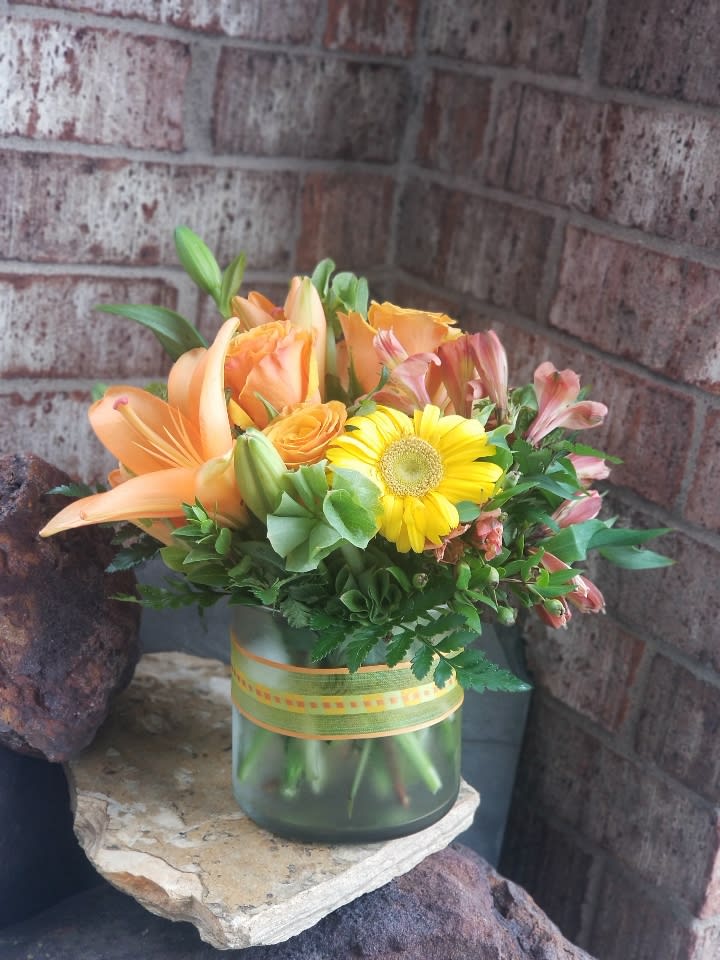 Sunny Siesta - Know someone who could use a little pick-me-up? Sending this pretty summer arrangement will definitely do the trick.  Vibrant orange roses, alstroemeria, orange asiatic lilies and gerberas are delivered in an organza ribbon-wrapped cylinder vase. Siesta or fiesta - it's all good.