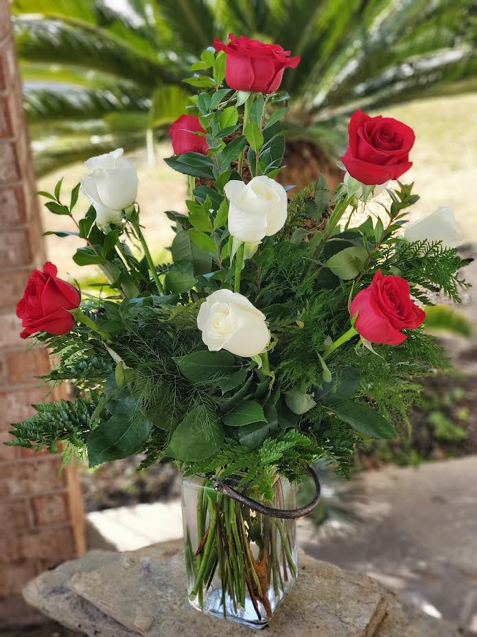 Red and white roses arranged in a clear glass vase