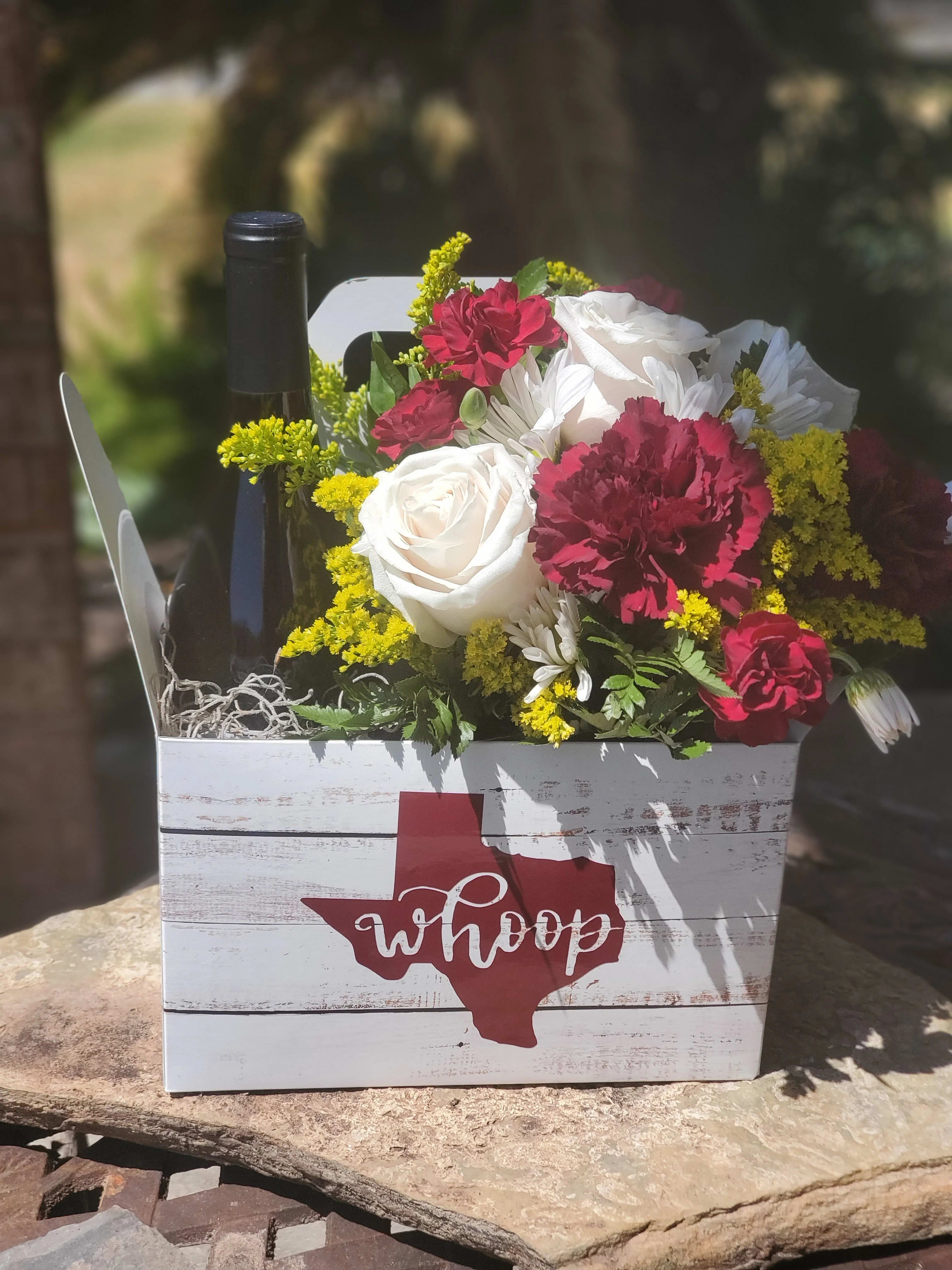 Flowers and a wine bottle in a white wooden gift box