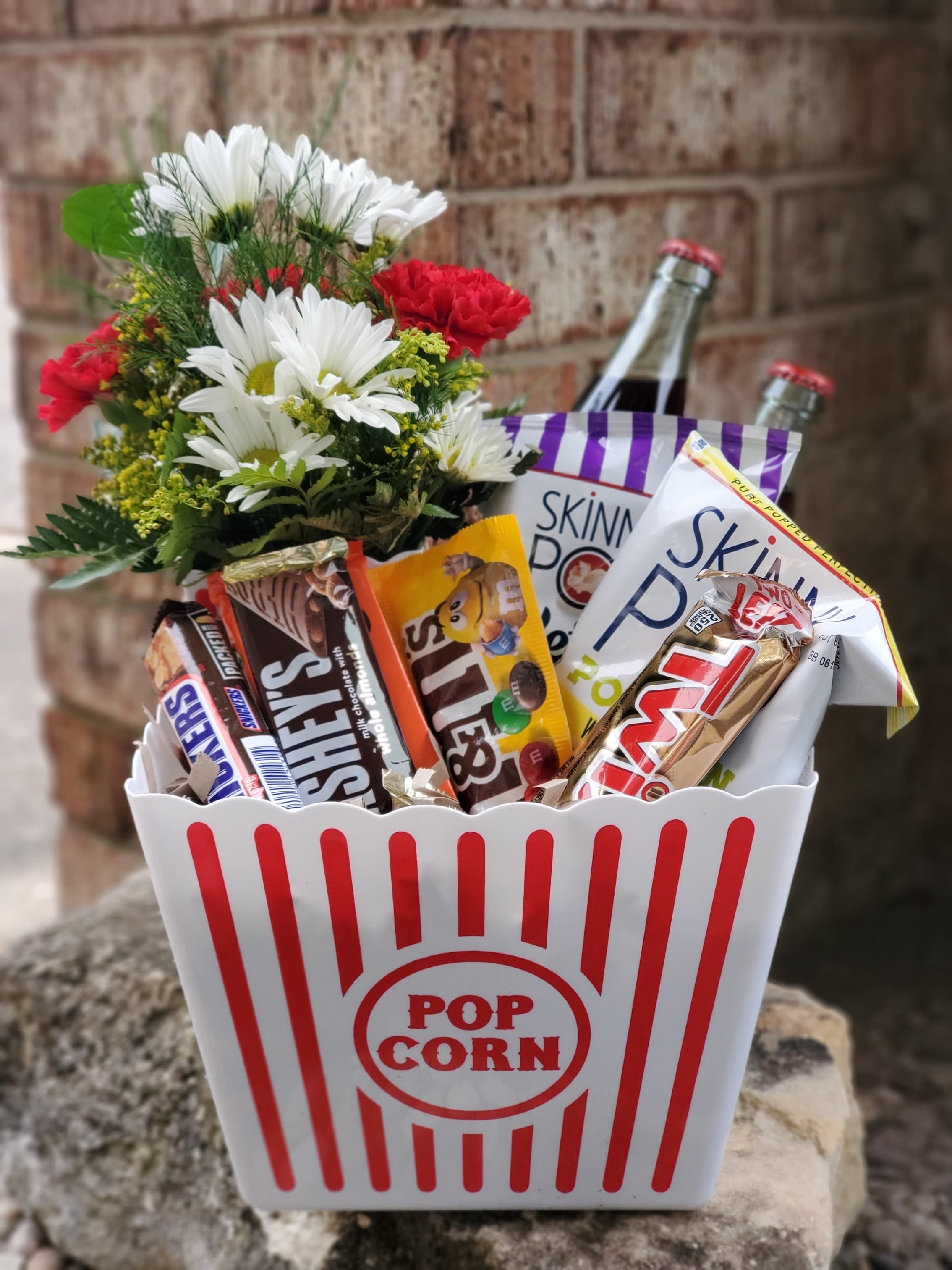 Popcorn bucket gift with candy bars and a small flower bouquet