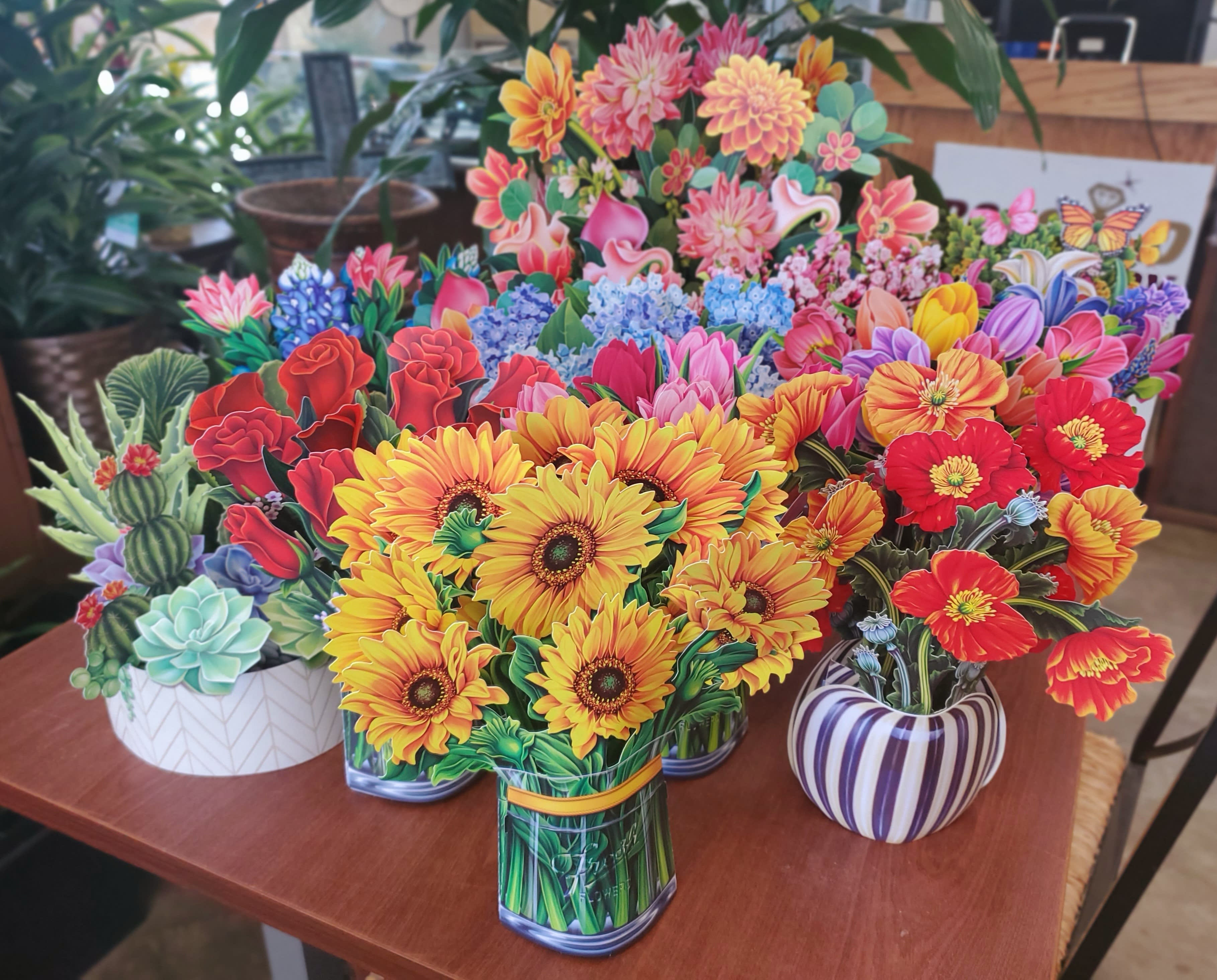 Colorful paper flower arrangements in patterned pots on a table